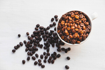 Roasted coffee beans in a coffee cup on a white table