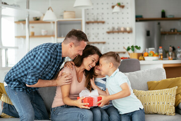 Two young sons are giving their mother a gift. Mother is suprised to receive a present from sons...