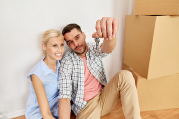 Fototapeta na wymiar mortgage, people and real estate concept - happy couple with key and boxes moving to new home
