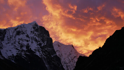 Fototapeta na wymiar Stunning sunset above ice-capped mountains in the Himalayas near village Thame, Khumbu, Nepal with dramatic colorful sky looking like the flames of a giant fire.