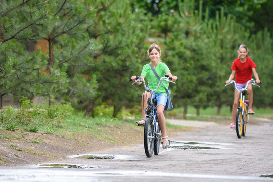 Two girls ride a bike on a rainy warm day