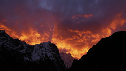 Spectacular sunset over snow-capped mountains in the Himalayas near Sherpa village Thame, Khumbu, Nepal with dramatic orange and purple colored sky looking like the flames of a giant fire.
