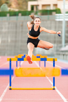 Fit Female Teenager Athlete Hurdler Running Jumping Over Hurdles