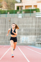 Fototapeta na wymiar Smiling fit female teenager athlete training on running track