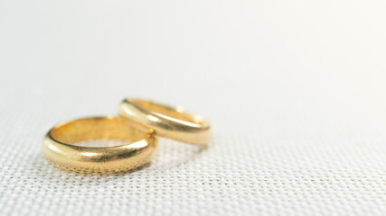 Close up of two gold rings for wedding on white sack background.