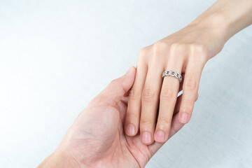 Man putting diamond ring on woman hand over white background.