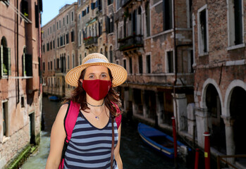 Fototapeta na wymiar young woman with mask and straw hat while visiting Venice during