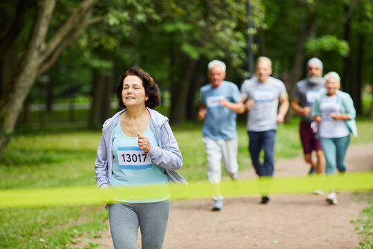 Active Sporty Mature Woman With Brown Hair Taking Part In Marathon Race Finishing It First, Copy Space