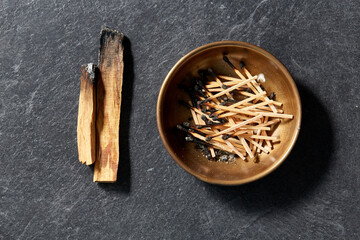 occult science and supernatural concept - palo santo sticks and cup with burnt matches