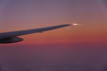 夕焼けの中上昇を続けるB-777-200主翼