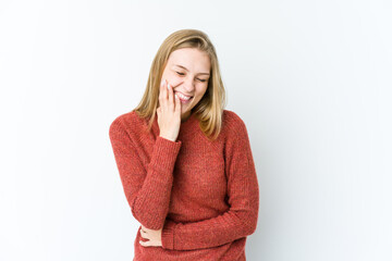 Young blonde woman isolated on white background laughs happily and has fun keeping hands on stomach.