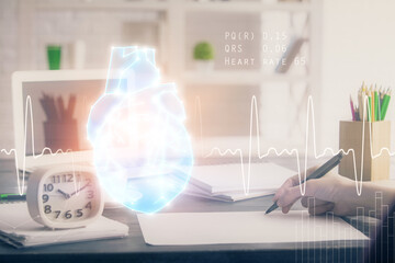 Heart hologram over woman's hands writing background. Concept of Medical study. Multi exposure