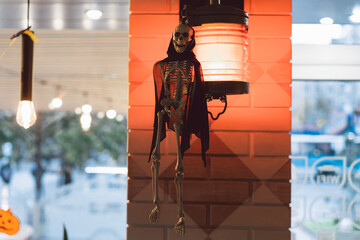 The Skeleton is hanging on a lantern in a cafe. Terrible creatures. Halloween concept