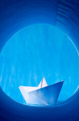Paper boat on blue. View through the spyglass imitation
