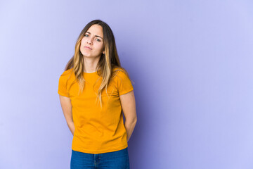 Young caucasian woman isolated on purple background sad, serious face, feeling miserable and displeased.