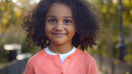 Close up of happy cute little african girl smiling at camera outdoors