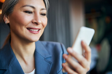 Beautiful cheerful woman texting message on smartphone