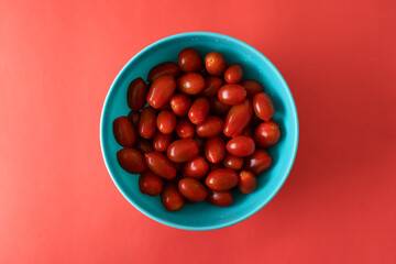 Top view of bowl with cherry tomatoes on a vibrant red background