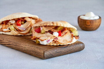 Shawarma with chicken  and garlic sauce in pita bread on wooden board. Closeup