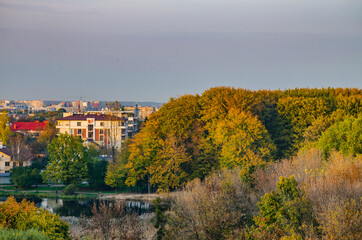 Landscape with autumn park in the sunny day. Yellow and green trees are displayed with reflection on the lake.