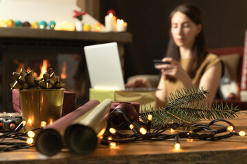 Gift workshop in a warm cozy room. Christmas decorations by fireplace. Ordering gifts online