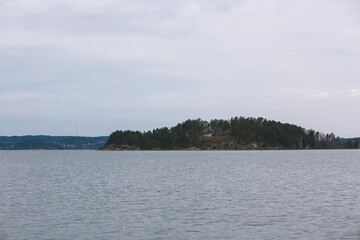 Cloudy ocean view with tree covered island at the horizon