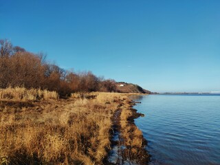 sunny autumn landscape on the river coastline against the blue sky