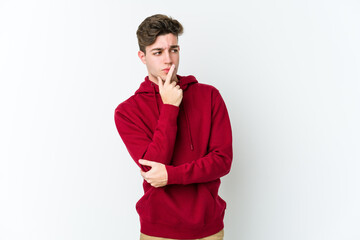 Young caucasian man isolated on white background looking sideways with doubtful and skeptical expression.