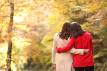 Couple of lesbian women walking in autumn in a forest