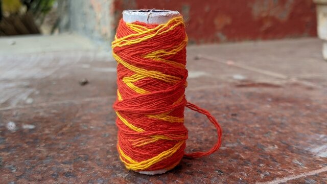 Cotton kalawa thread role or Mauli used in Hindu's for wearing in wrist during puja (worship). Closeup view of Red religious cotton thread in indian temple