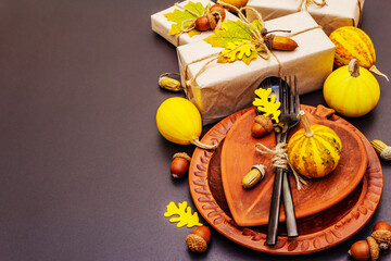Autumn table setting with crafted gift boxes, fall decor and black cutlery