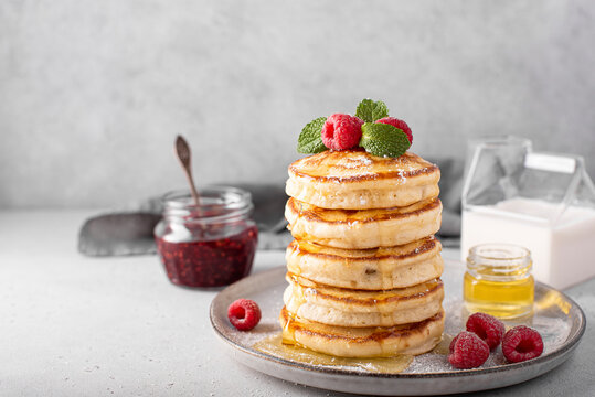 a stack of lush pancakes with raspberries and honey