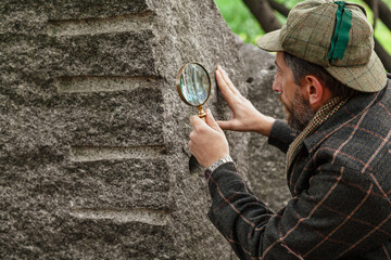 Scientist examines block of sandstone through magnifying glass