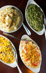 Steakhouse side dishes. Asparagus, salad, tomatoes, mashed potatoes, red onions, cream cauliflower, pickled peppers, seasoned meats served in cast iron skillet. Traditional appetizer items.