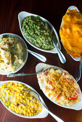 Steakhouse side dishes. Asparagus, salad, tomatoes, mashed potatoes, red onions, cream cauliflower, pickled peppers, seasoned meats served in cast iron skillet. Traditional appetizer items.