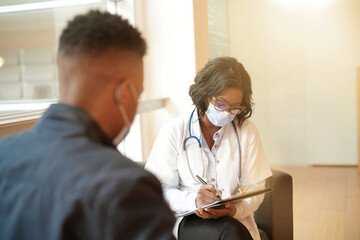 Fototapeta premium Woman doctor with patient in office, check-up for 19-ncov