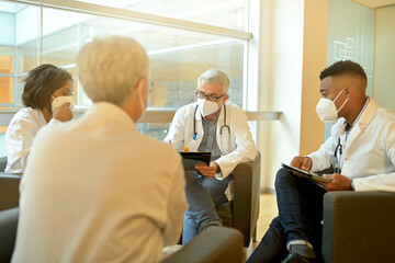 Fototapeta premium Medical people sitting in meeting room, checking planning together during pandemic
