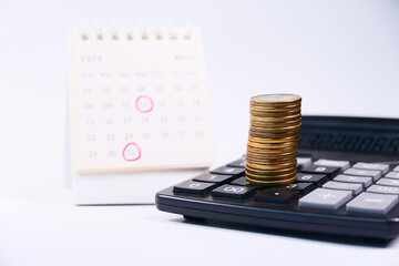 stack of coins and calendar on white background 