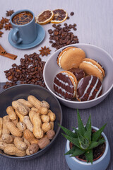 A cup of espresso is decorated with anise stars, cinnamon, sweets, dried lemons, acorns, peanuts in a beautiful dish.