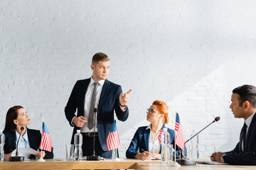 Serious politician pointing with finger while standing and looking at colleague during political...