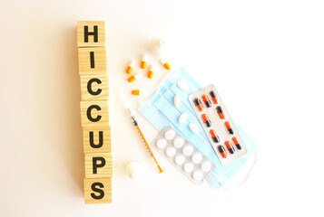 The word HICCUPS is made of wooden cubes on a white background. Medical concept.