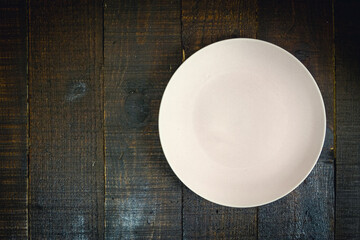 Empty pink ceramic plate on wooden background dark tone, copy space.