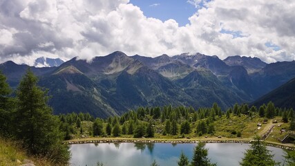 Fototapeta na wymiar A lake in the Italian Alps with a forest and mountains in background (Trentino, Italy, Europe)