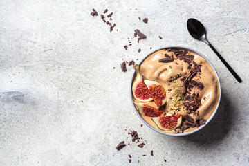 Chocolate smoothie bowl or vegan ice cream with figs and hemp seeds, gray background, copy space. Healthy vegan food concept.