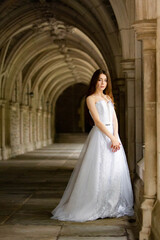 Beautiful girl wearing white wedding dress posing alone at a castle hall