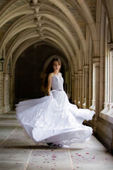Fototapeta na wymiar Beautiful girl wearing wedding dress spinning in the hall
