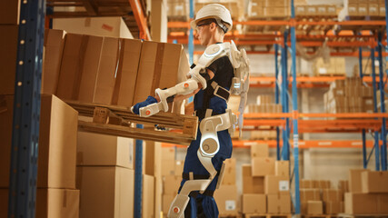 High-Tech Futuristic Warehouse: Worker Wearing Advanced Full Body Powered exoskeleton, Lifts Heavy...