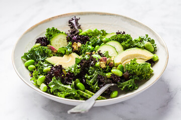 Green and purple kale salad with edamame beans, avocado and cucumber. Healthy vegan food concept.