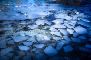 Reflections of snow capped mountains in a blue icy lake in the mountains