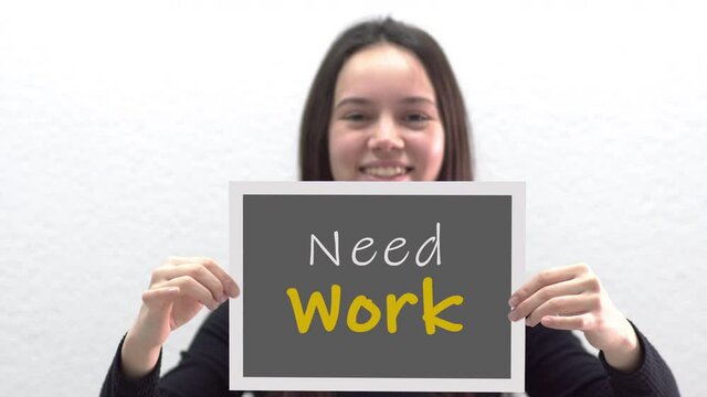 Conceptual message "Need Work" on canvas frame label hold by beautiful girl smiling at camera